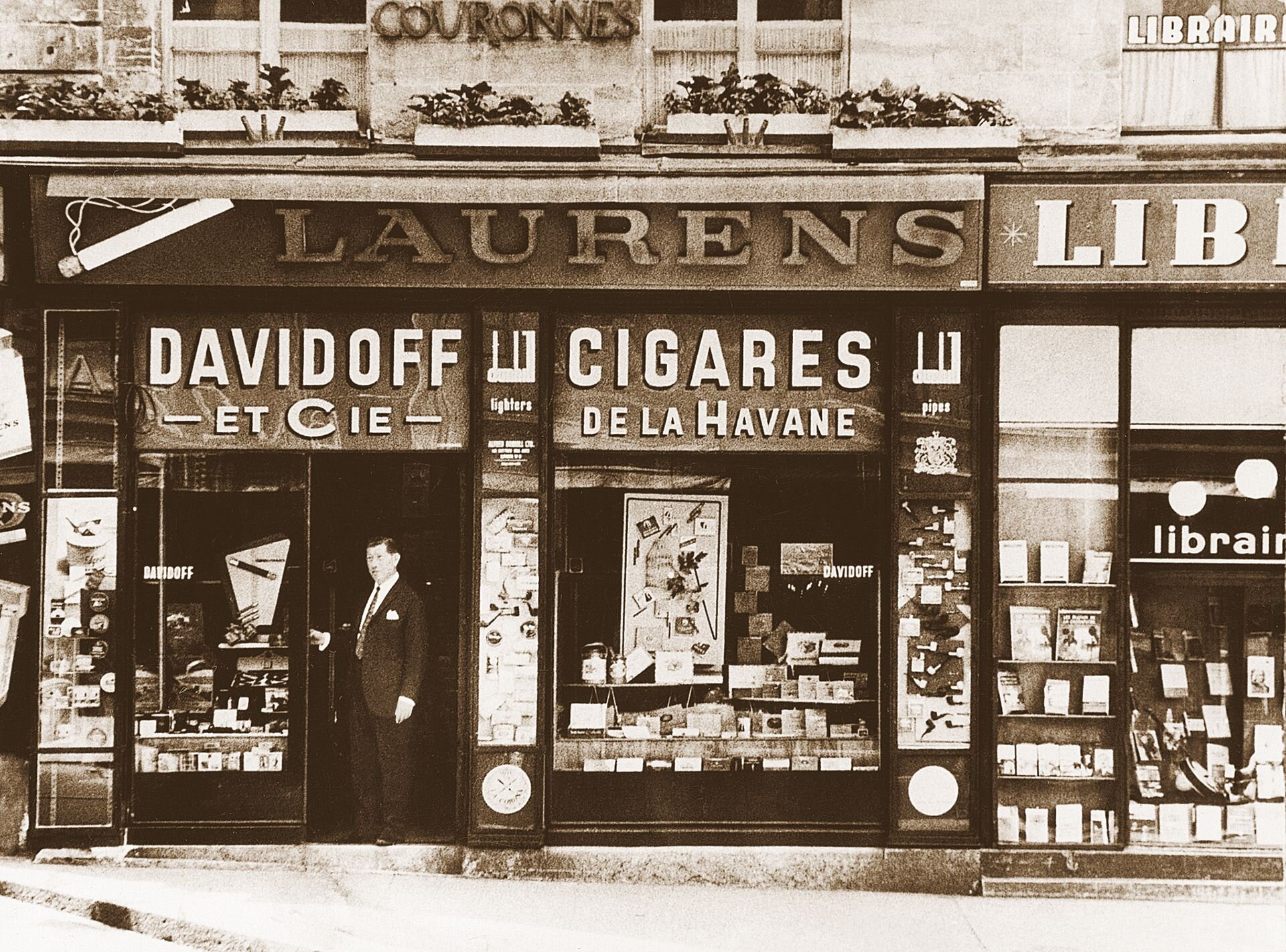 A vintage storefront featuring a man in a suit, promoting Davidoff cigars at the Davidoff store in Geneva. The image has a sepia tone.