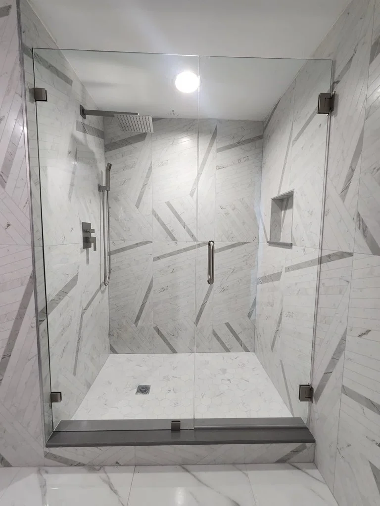 Clear glass shower enclosure in a marble-tiled bathroom