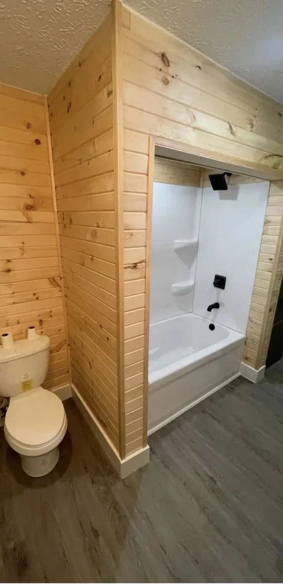 Completed bathroom renovation with white tub surround, vanity and black fixtures