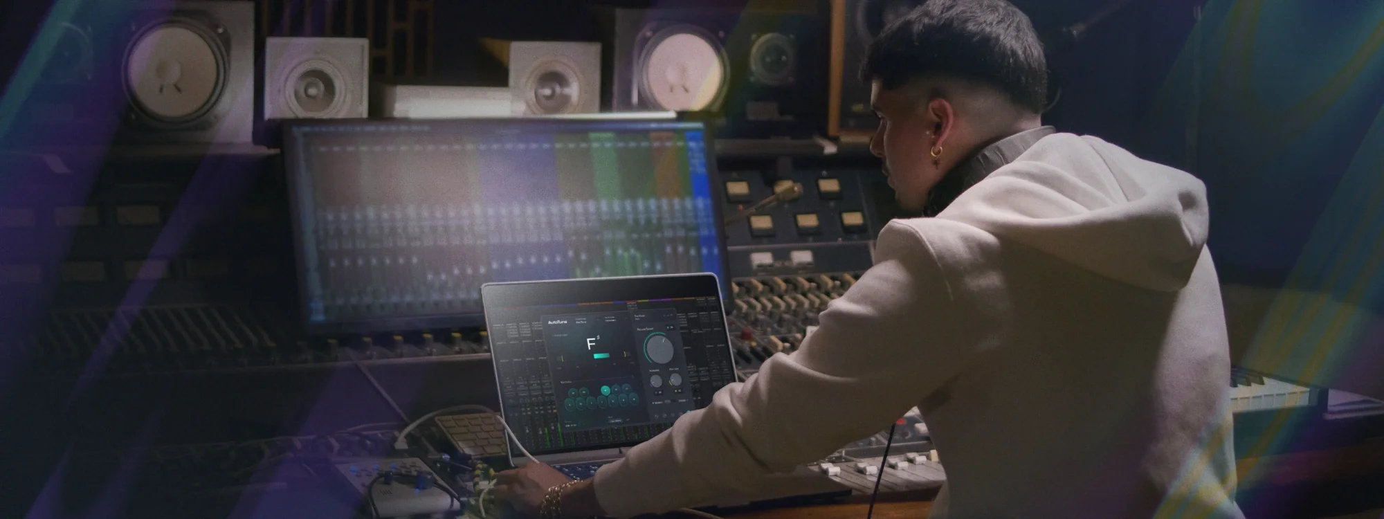A man in a studio sitting in front of a computer running AutoTune