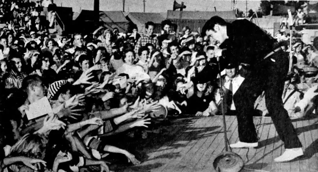 Elvis Presley performing on stage in front of a huge crowd