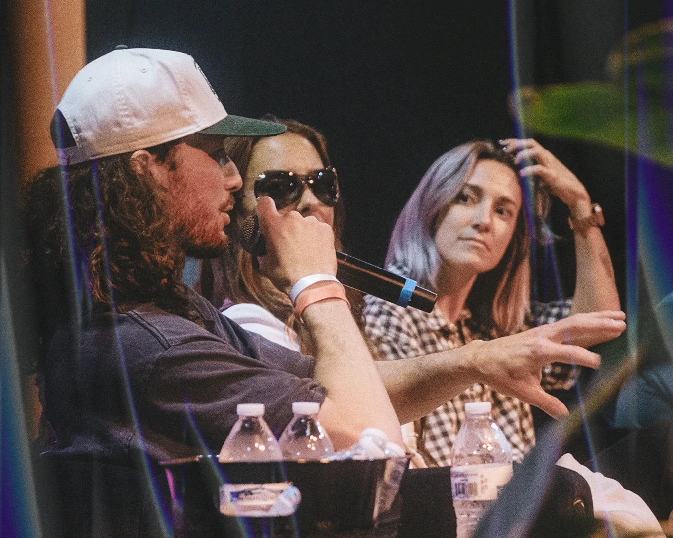 A man speaking into a microphone sitting next to two other people
