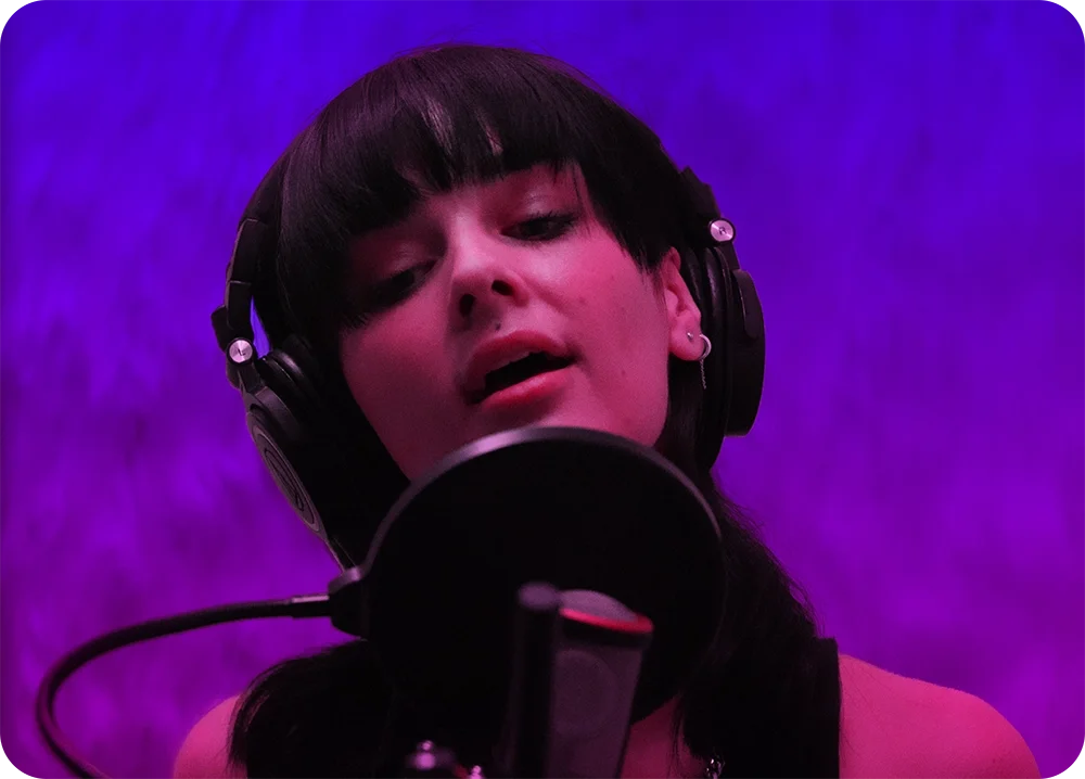 A girl singing in a microphone with purple lighting