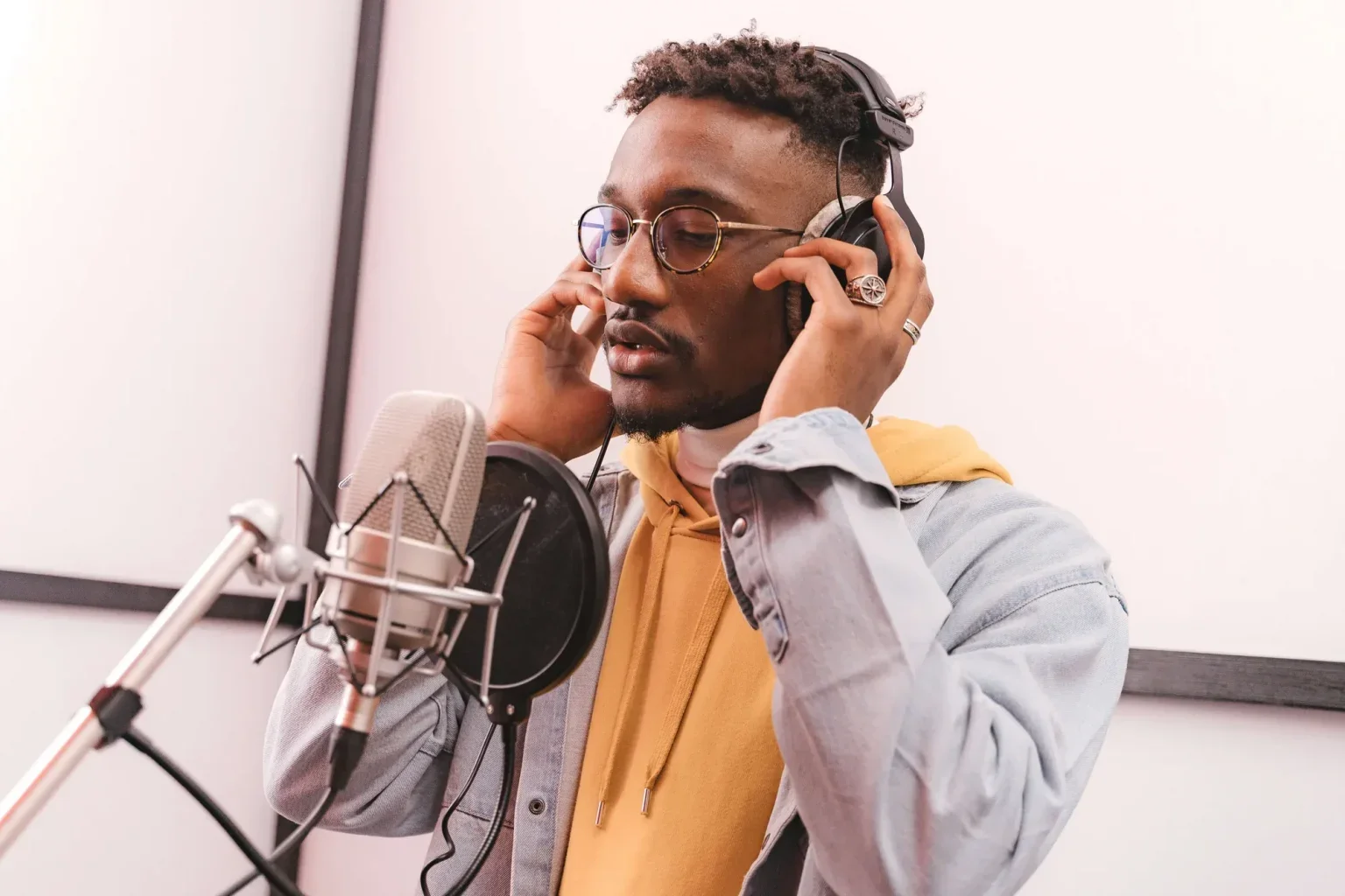 Man standing in front of a microphone, holding headphone over his ears
