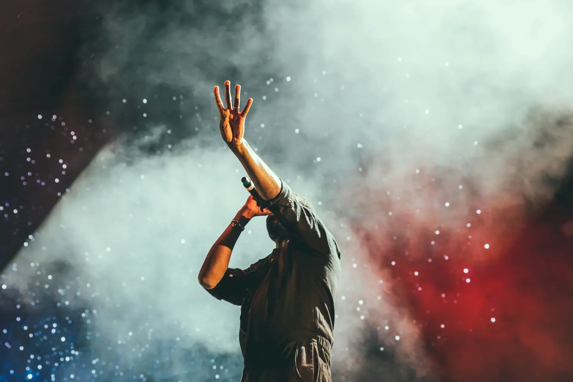 A man with his hand raised signing into a microphone