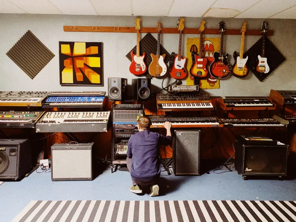 Man kneeling on the floor looking for something in a home studio.