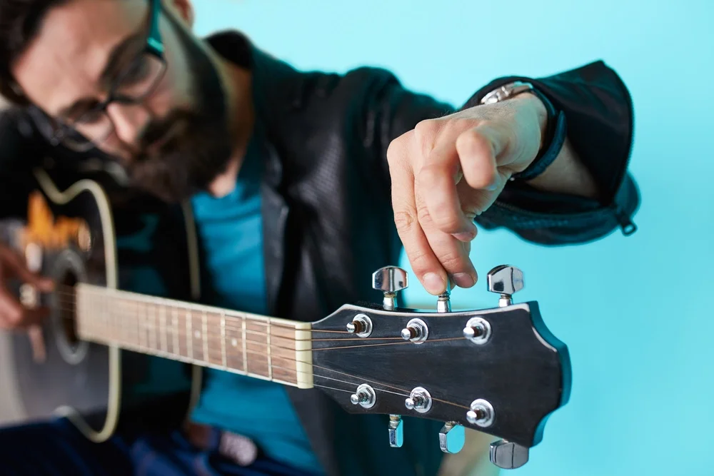 A man tuning a acoustic guitar