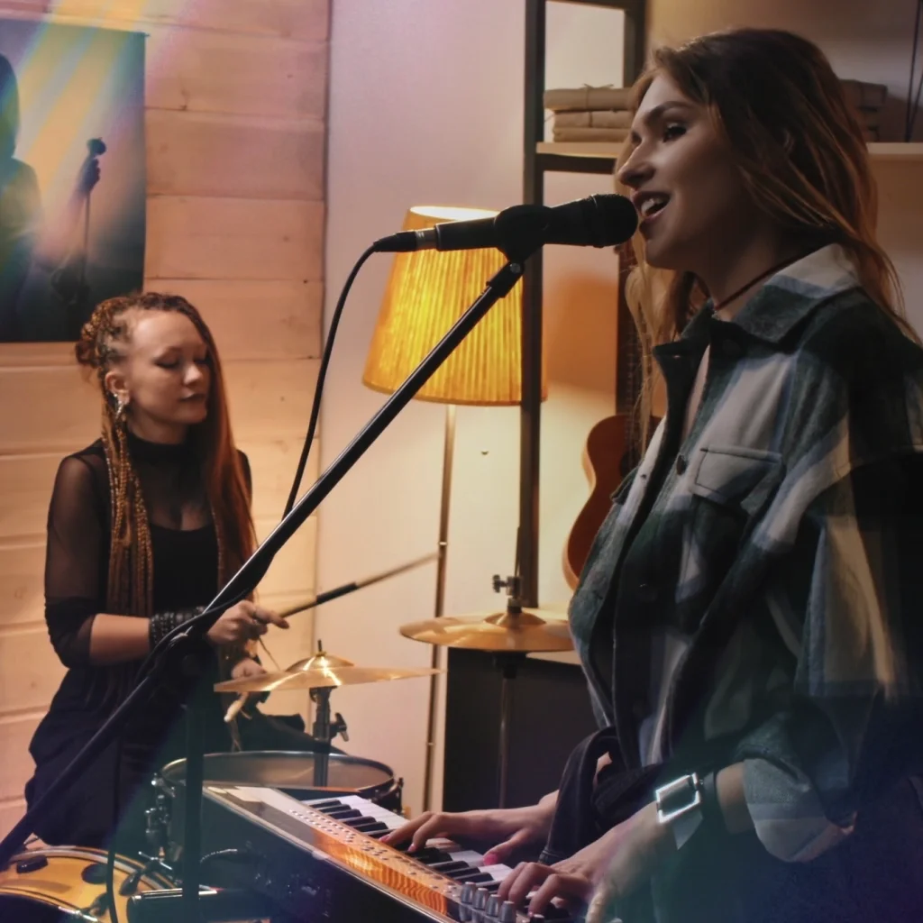 Three woman playing instruments and singing in a garage band