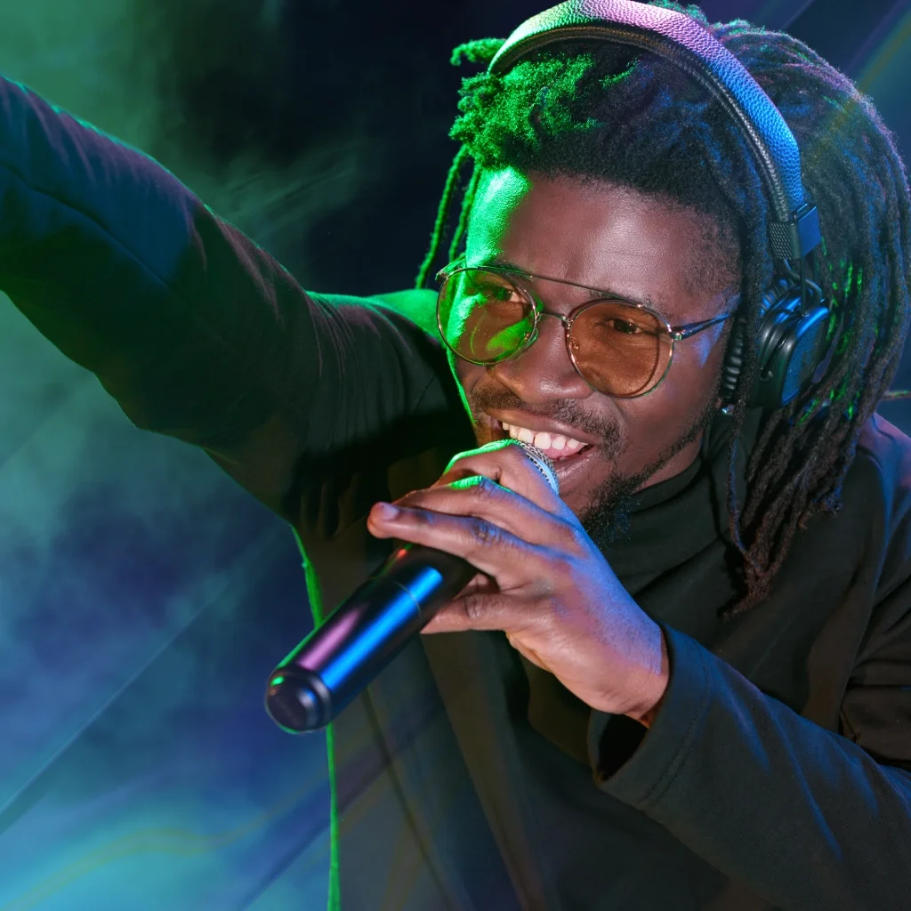 A man wearing headphones singing into a microphone he's holding in his hand