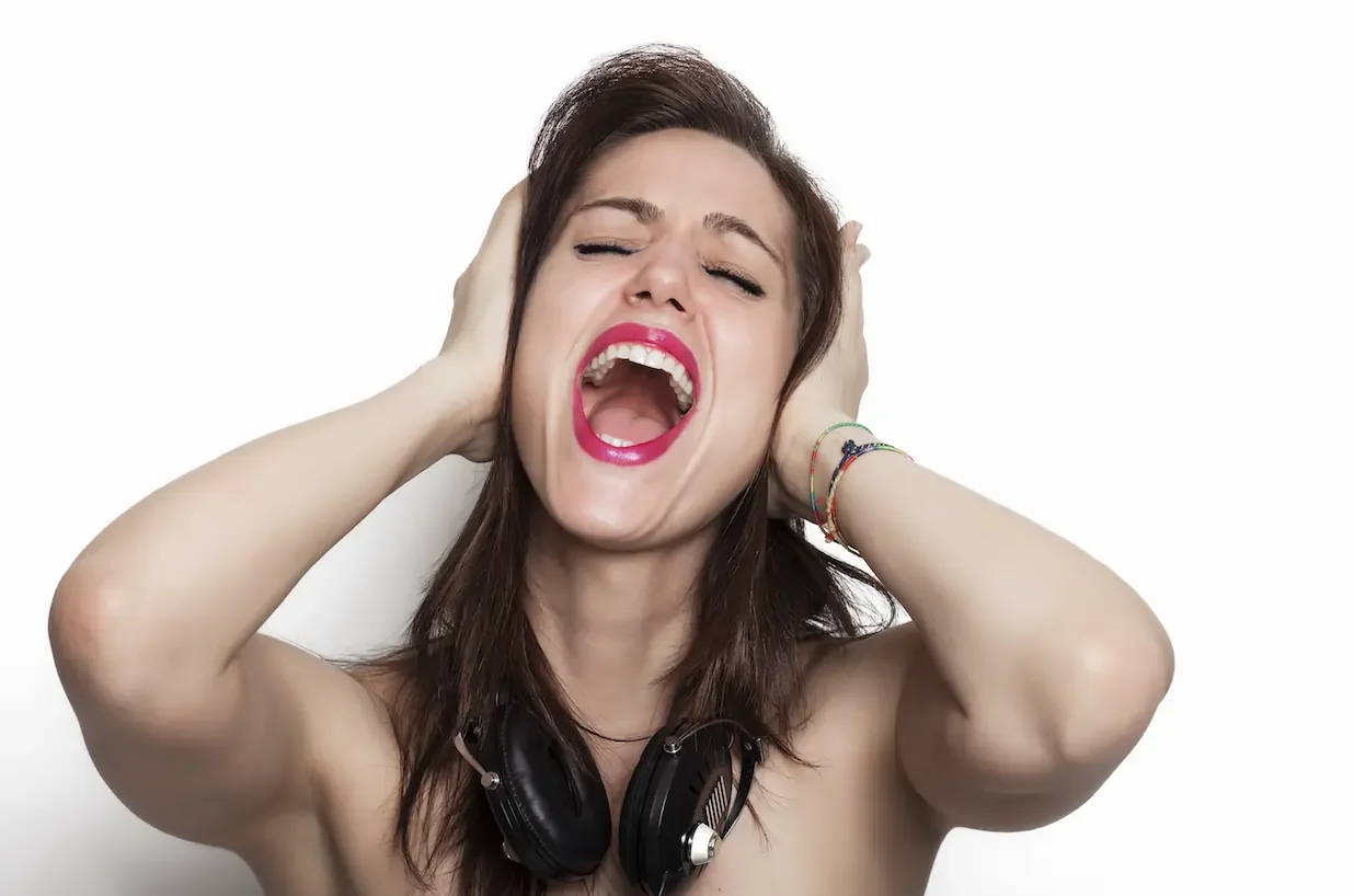 A woman with her singing with her hands covering her ears