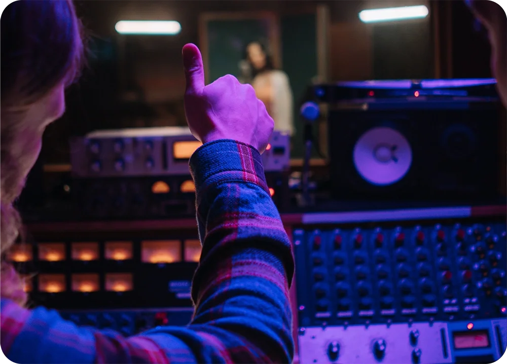 A recording engineer giving a singer in the recording booth a thumbs up