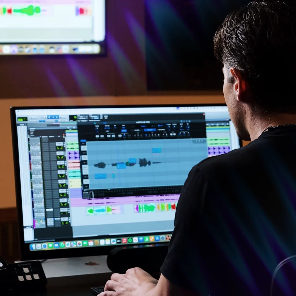 A man sitting in front of a computer running a DAW