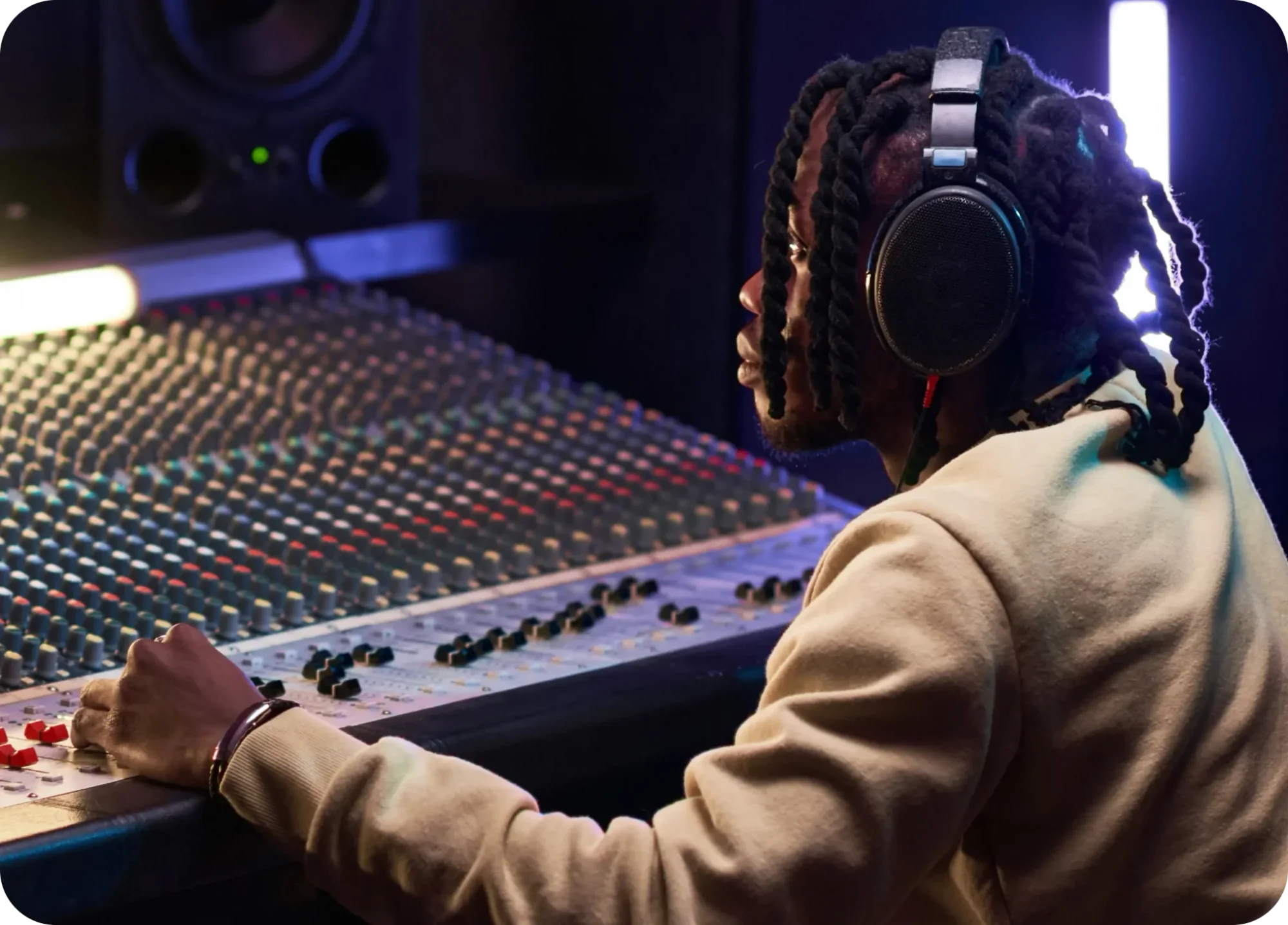 A male working at mixing board console in a recording engineer room