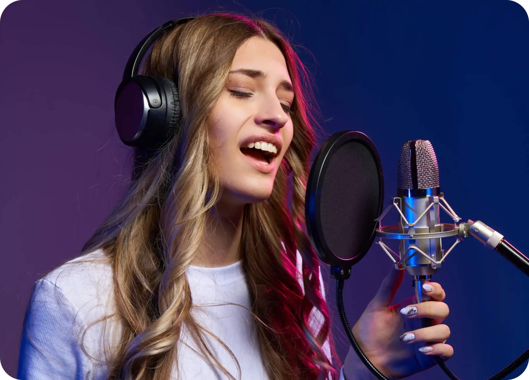 A female holding onto microphone while singing and wearing headphones