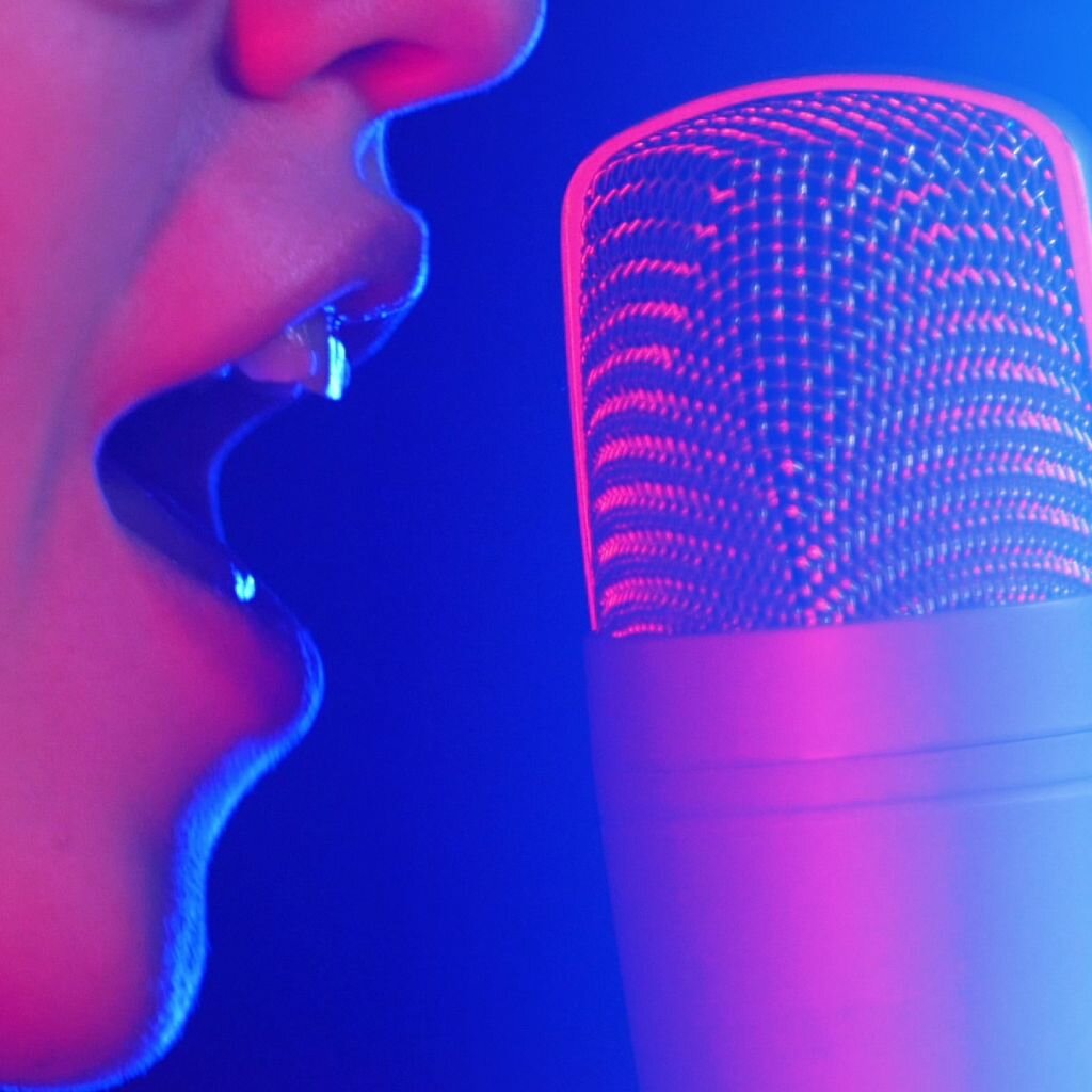 Close up of a females face singing into a microphone