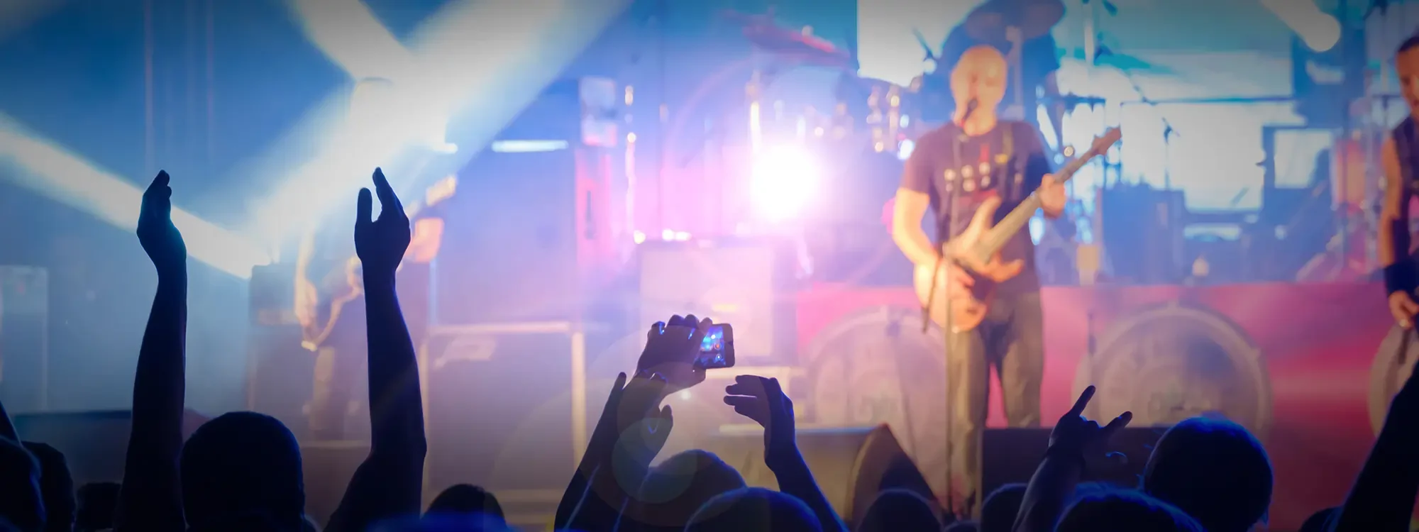 A man playing the guitar and singing on stage in front of an audience