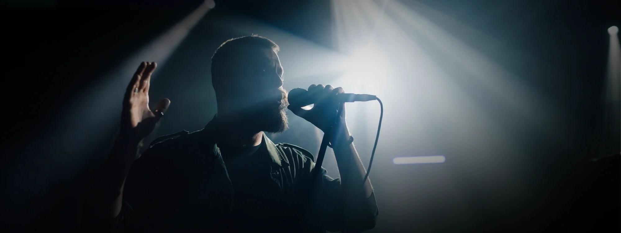 A man singing into a microphone with a spotlight on him