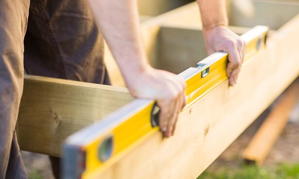 A contractor uses a level on a deck frame.