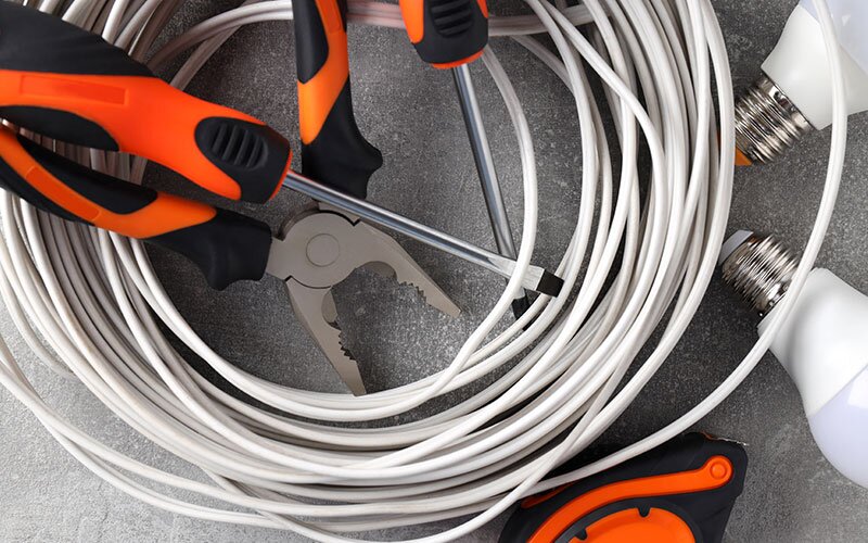 Electrical products piled together, including wiring, light bulbs and tools.