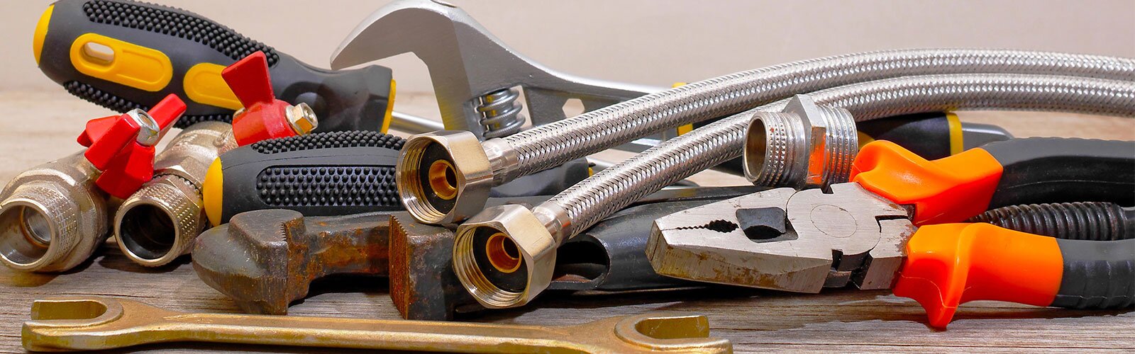 Up close of plumbing tools with a variety of supplies: valves, hoses, etc. 