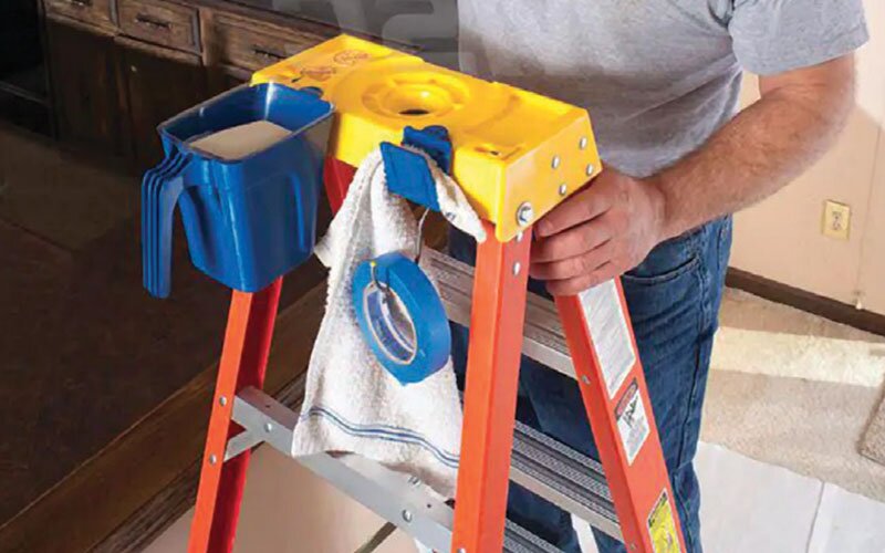 A man with a painting accessory attached to a ladder.