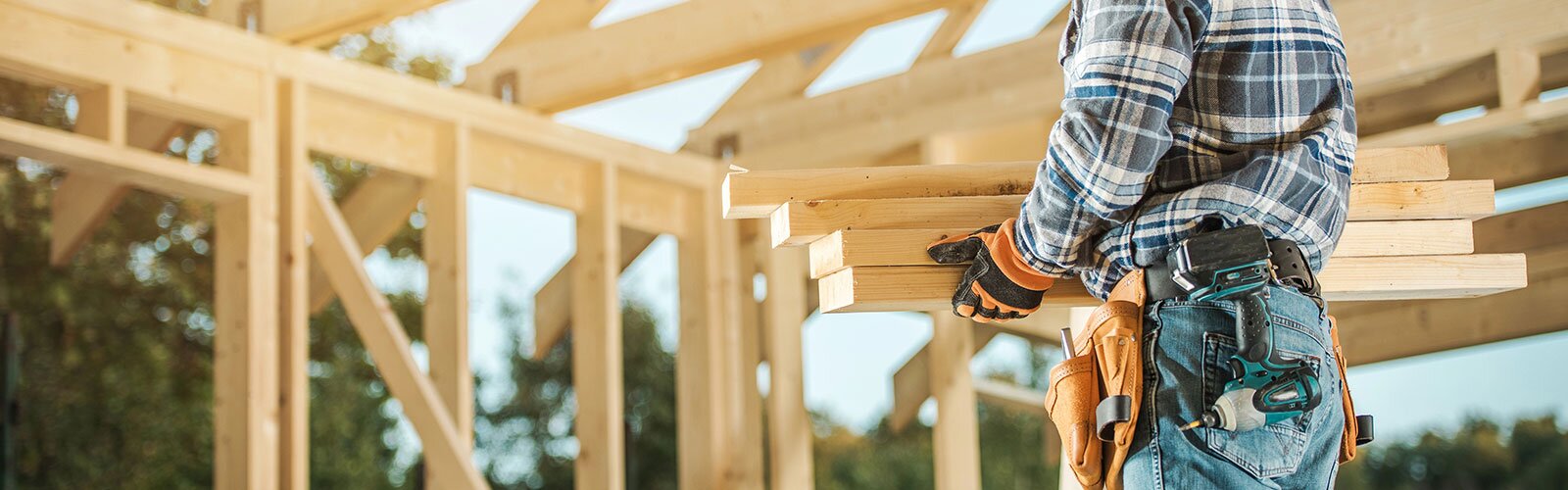 A contractor holding lumber on a job site.