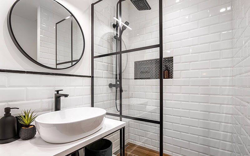 A black and white bathroom, tiled with beveled subway tile and black hardware and accessories. 