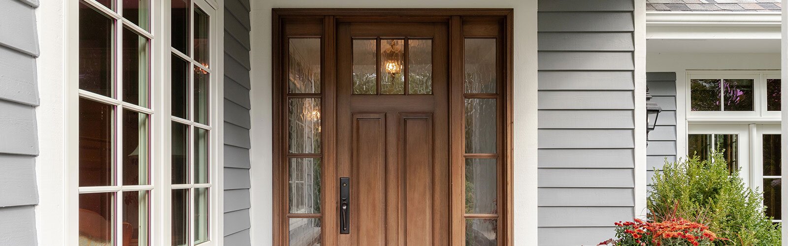 An exterior home with a wooden traditional front door and windows.