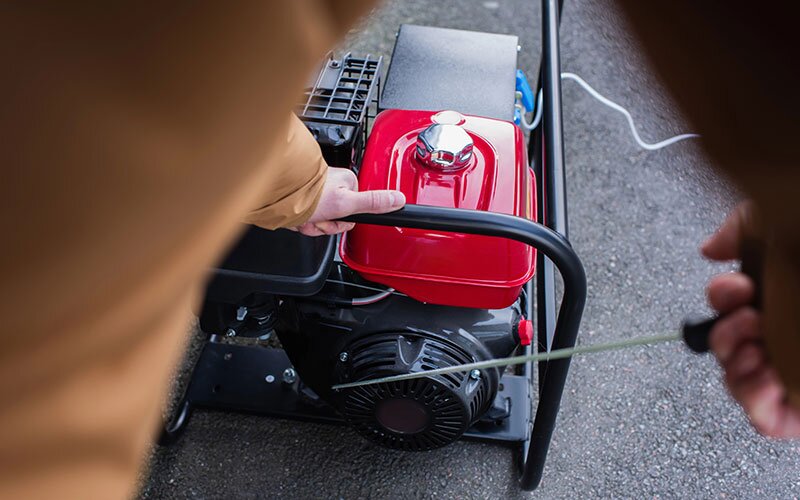 A man pulls on the cord to start a generator.