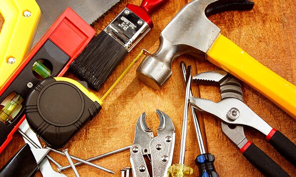 A variety of hand tools and fasteners on a wooden surface.