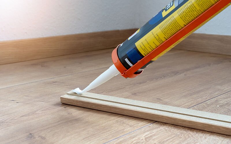 Glue is being applied to a piece of floor trim.