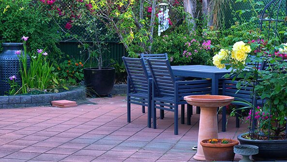 An outdoor patio with patio stone, garden edging and patio table and chairs.