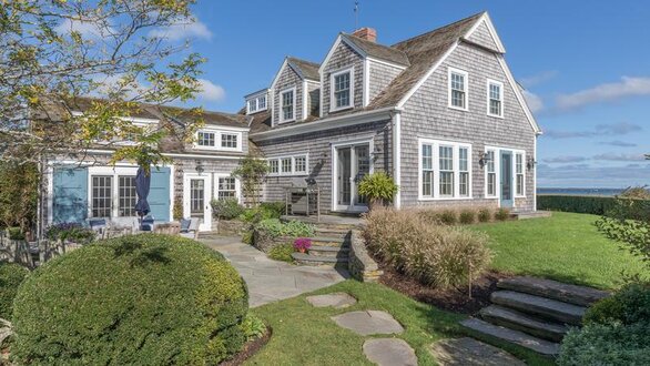 Exterior view of Shearwater with small patio area on stone with steps that lead up to front yard