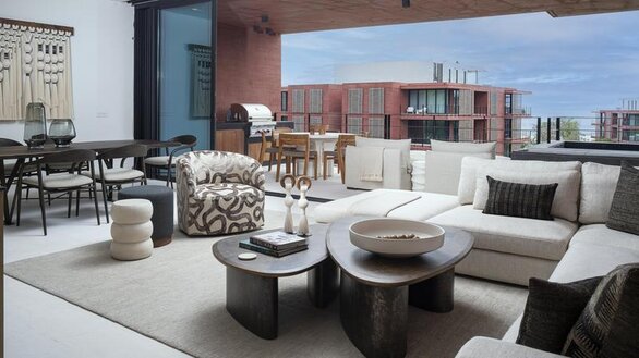 Living area with a variety of furniture with a large wooden table that seats eight with a sliding glass wall that leads out to terrace