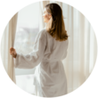 A woman looking out a window while wearing a plush robe