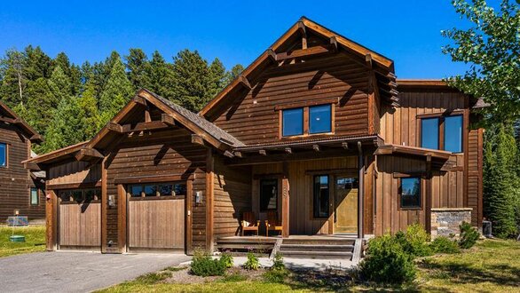 Front exterior of Flatiron with a driveway leading up to a two car garage with steps leading up to the front door