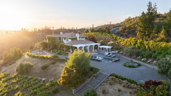 Aerial view of Villa Della Luna property with surrounding vineyard, small pool, and the sun setting in the distance
