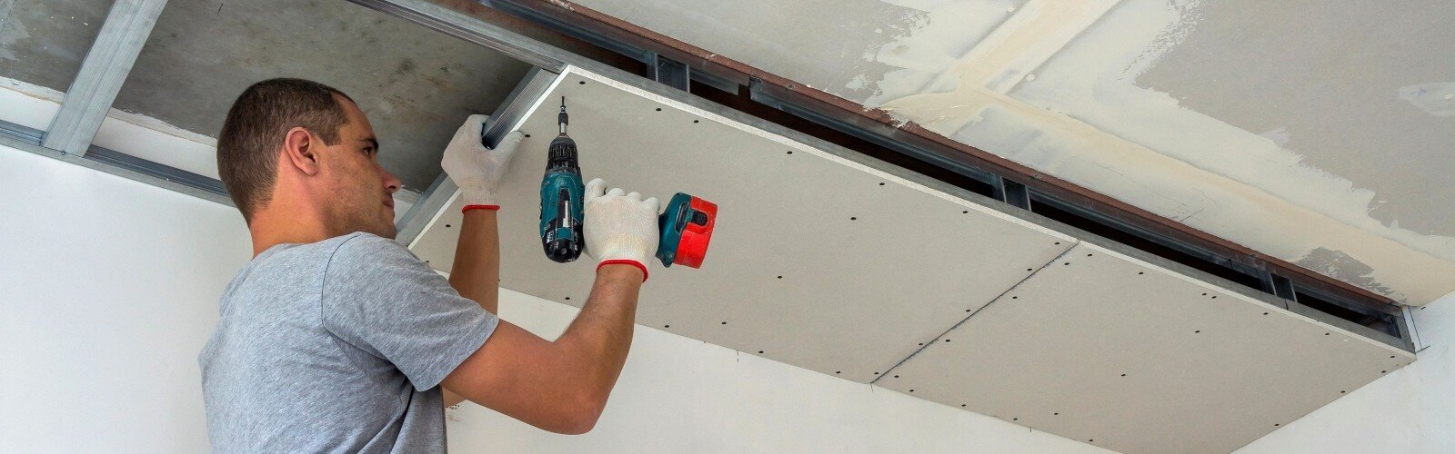 Construction worker assemble a suspended ceiling with drywall