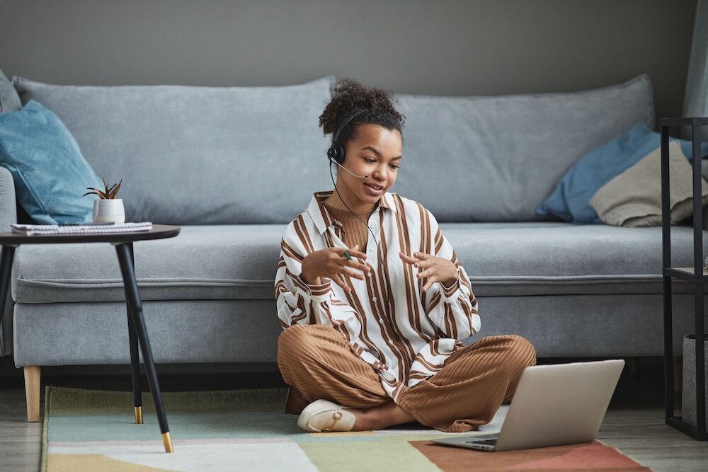 Patient thoughtfully speaking with psychotherapist via a virtual therapy session