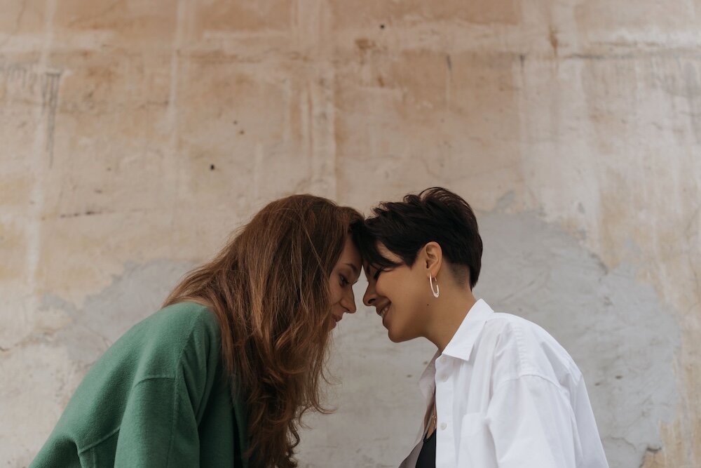 Two people smiling and touching their foreheads together
