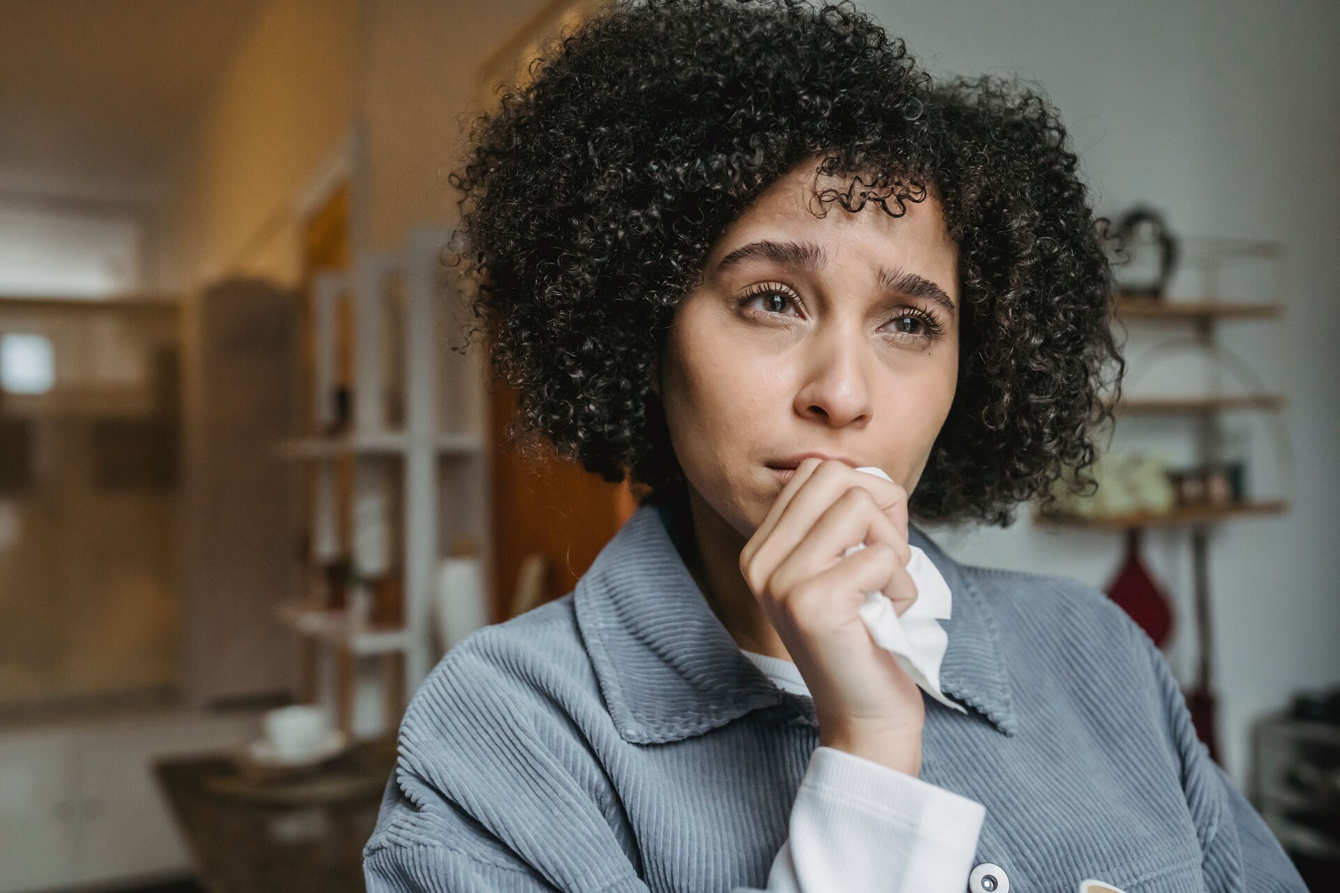Woman looks forward nervously with her hand in front of her mouth
