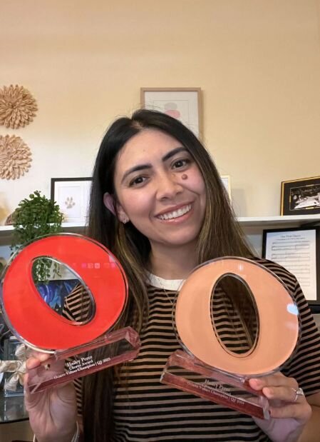 A smiling woman outdoors with a blue sky in the background.