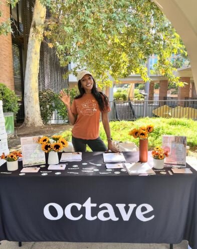A smiling woman outdoors with a blue sky in the background.