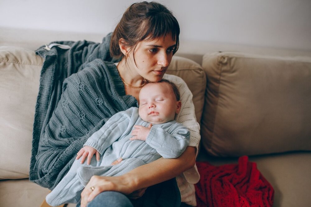 New mother holding baby and looking pensive