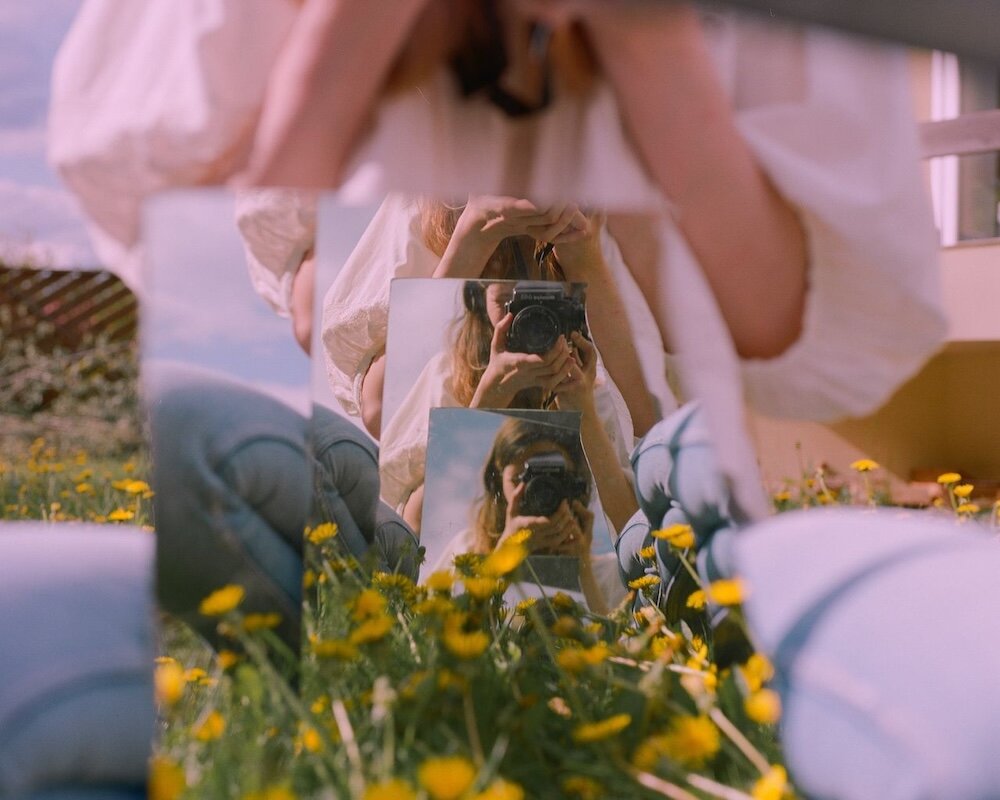 Person taking a photo of themselves reflected back in multiple mirrors