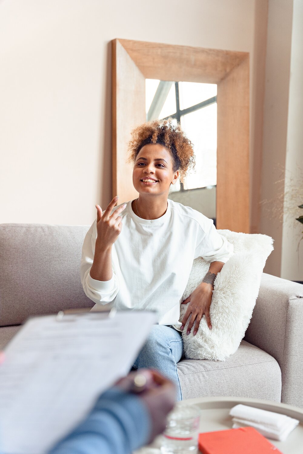 A seated woman smiling while speaking with a therapist
