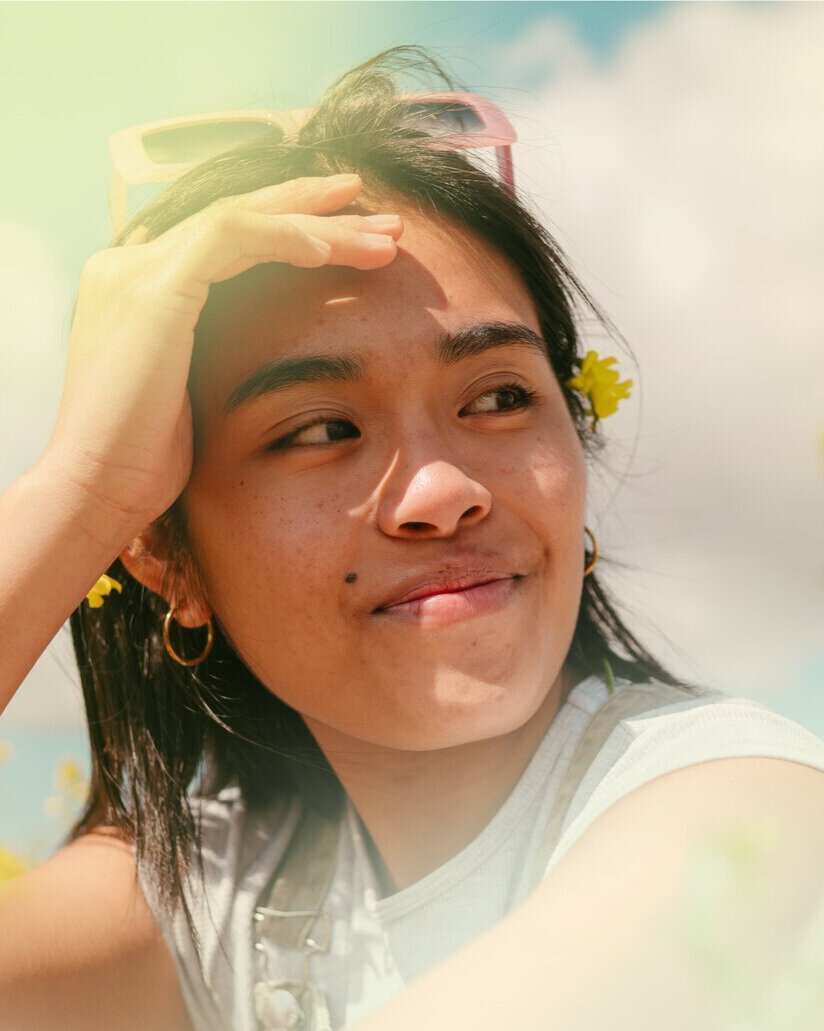 A smiling woman outdoors with a blue sky in the background.