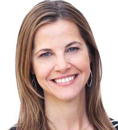A smiling woman outdoors with a blue sky in the background.