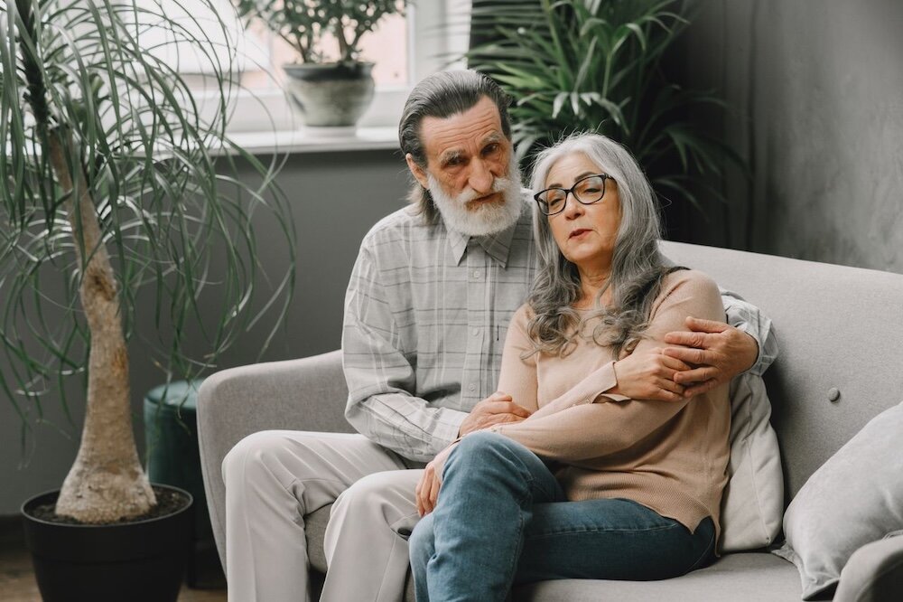 Two people sitting on a gray couch