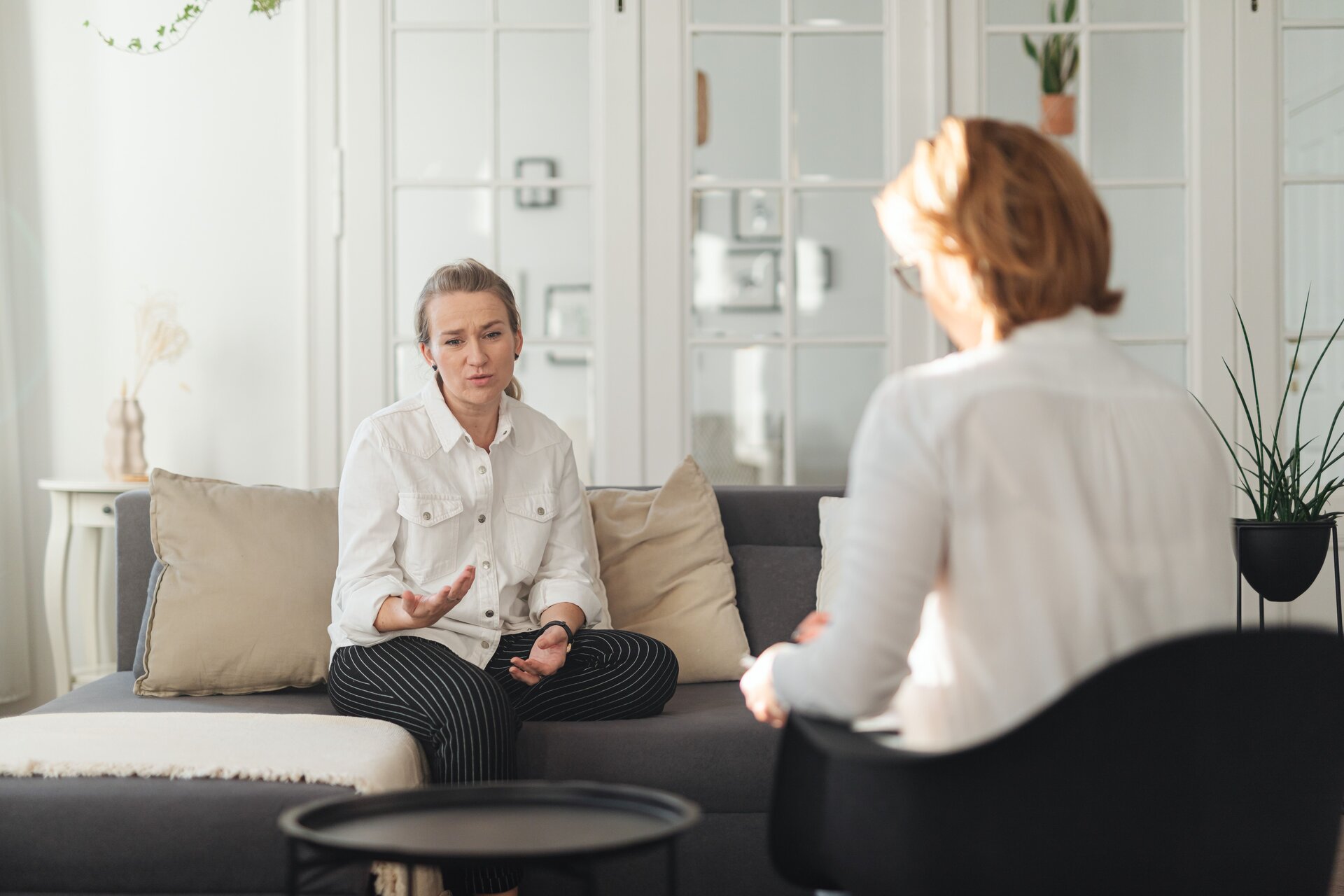 Patient sitting on a couch and thoughtfully speaking with a psychiatrist